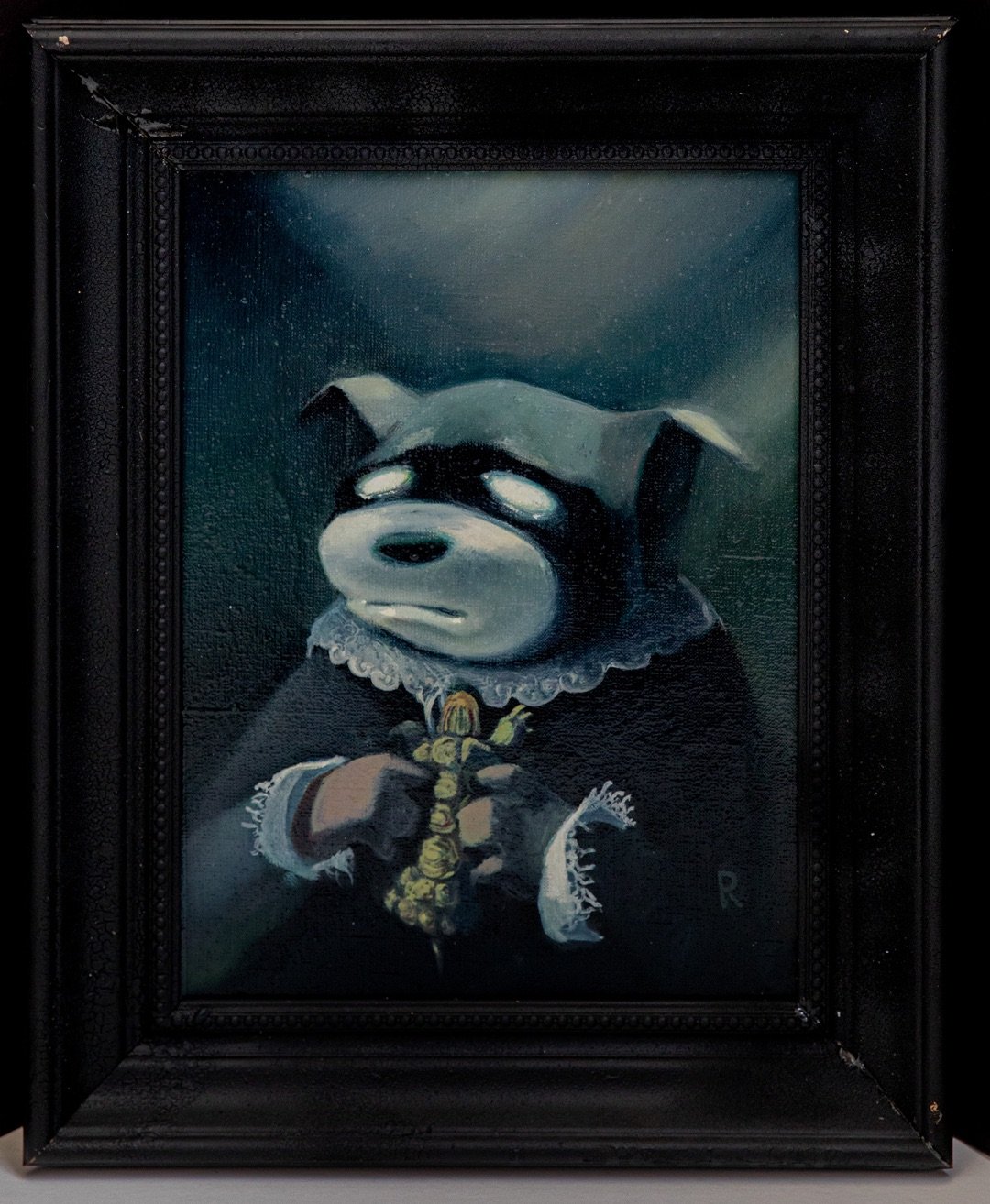 Dark portrait of a dog in a lace collar holding a dried flower